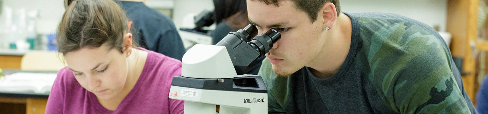 Male student looking through telescope